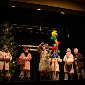 Ośmioro przebranych za pastuchów występuje na scenie. Jeden z nich trzyma kolorową gwiazdę na kiju.